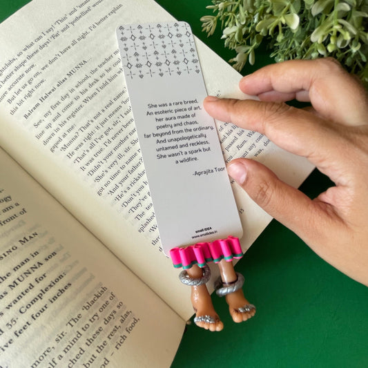 miniature tribal legs with pink skirt and green border as a bookmark attached to aprajita toor's poem